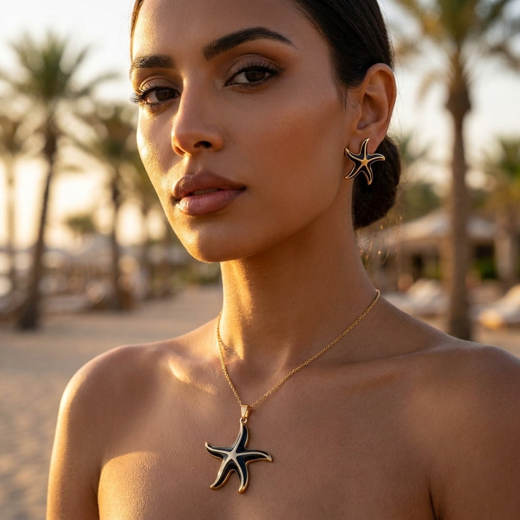 Femme portant la parure étoile de mer noire et dorée sur la plage au coucher du soleil